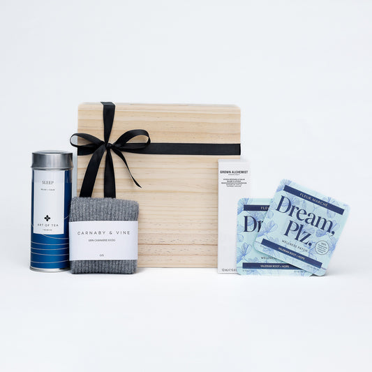 Gift set with a wooden box, tea canister, socks, and packets on a white background