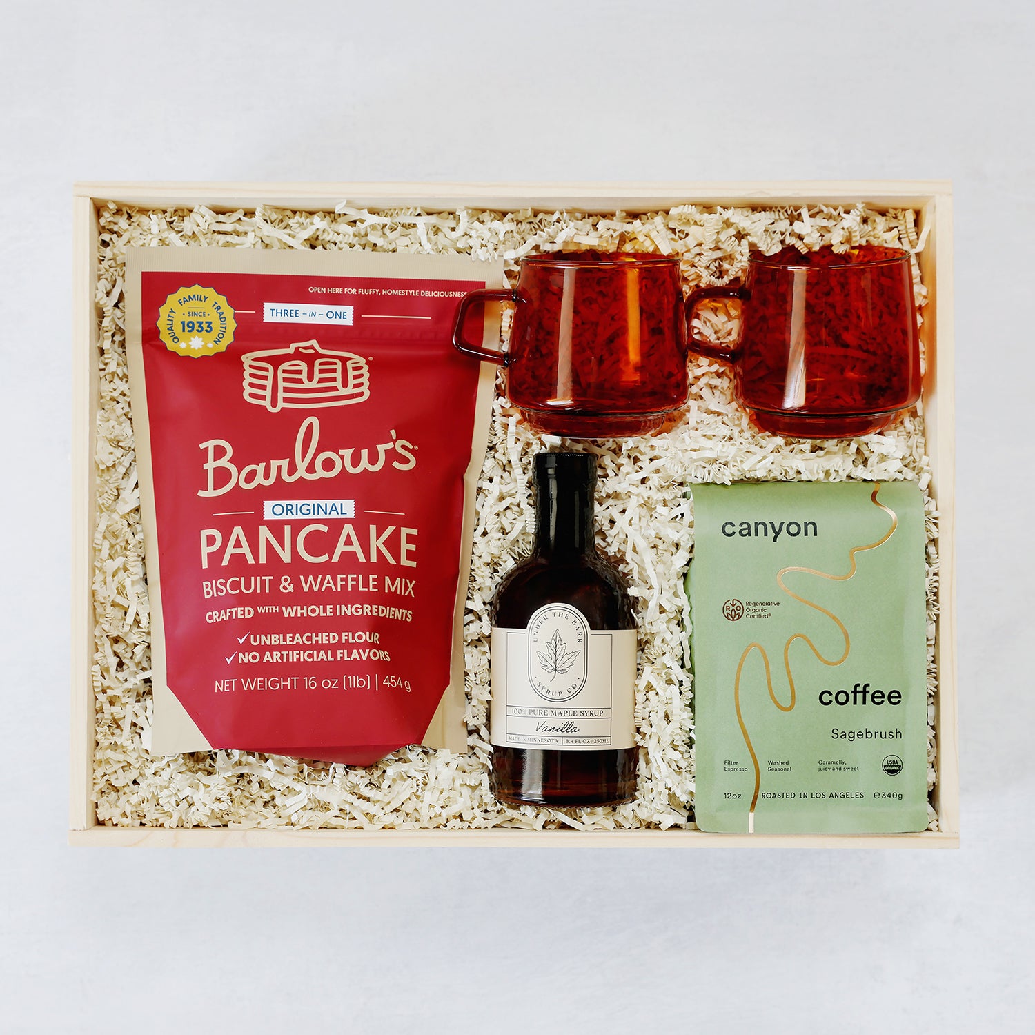Gift set with Barlow's pancake mix, two amber mugs, a bottle of vanilla extract, and a coffee package in a wooden box.
