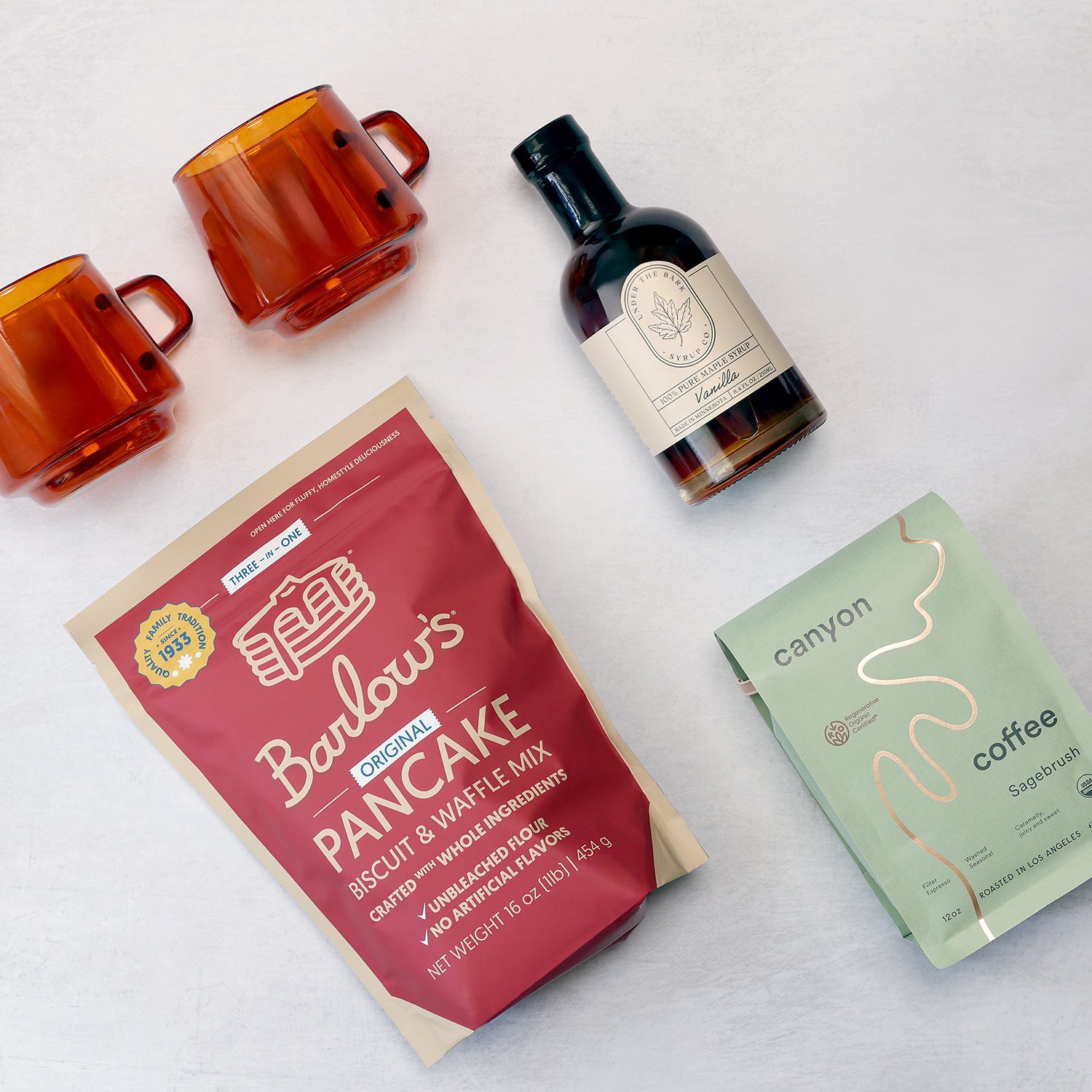 Holiday gift box including barlowe's pancake mix, kinto mugs, vanilla maple syrup, and canyon coffee grouped together on a light gray background.