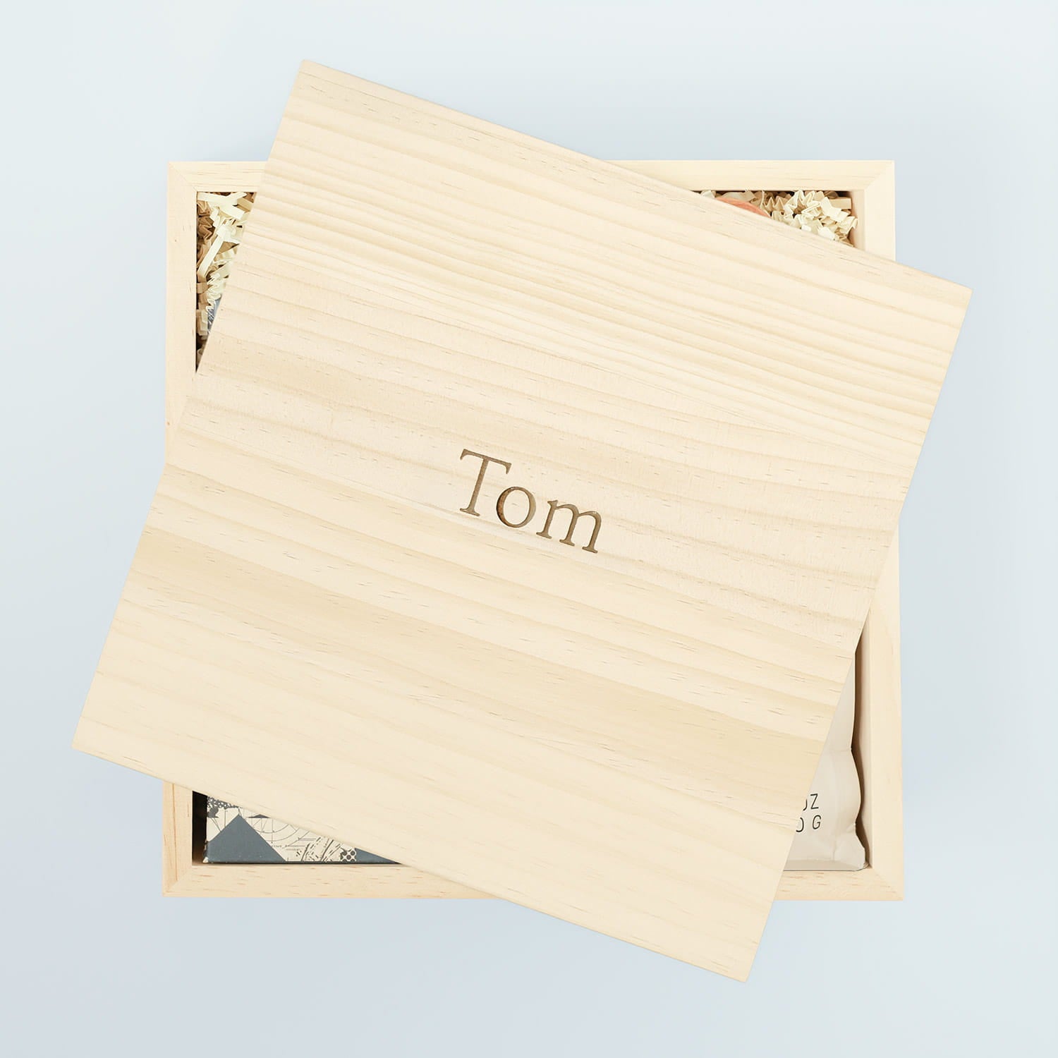 Wooden box with 'Tom' engraved on it against a light blue background