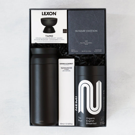 Gift set with black tumbler, Tamo speaker, and candle, hand cream and Nemi tea on a light gray background.