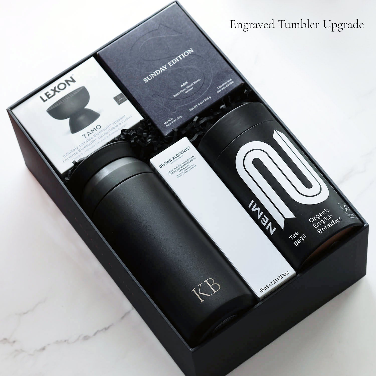 The contents of the Elite Retreat gift box including a monogrammed Kinto tumbler. Items in box on a marble surface.