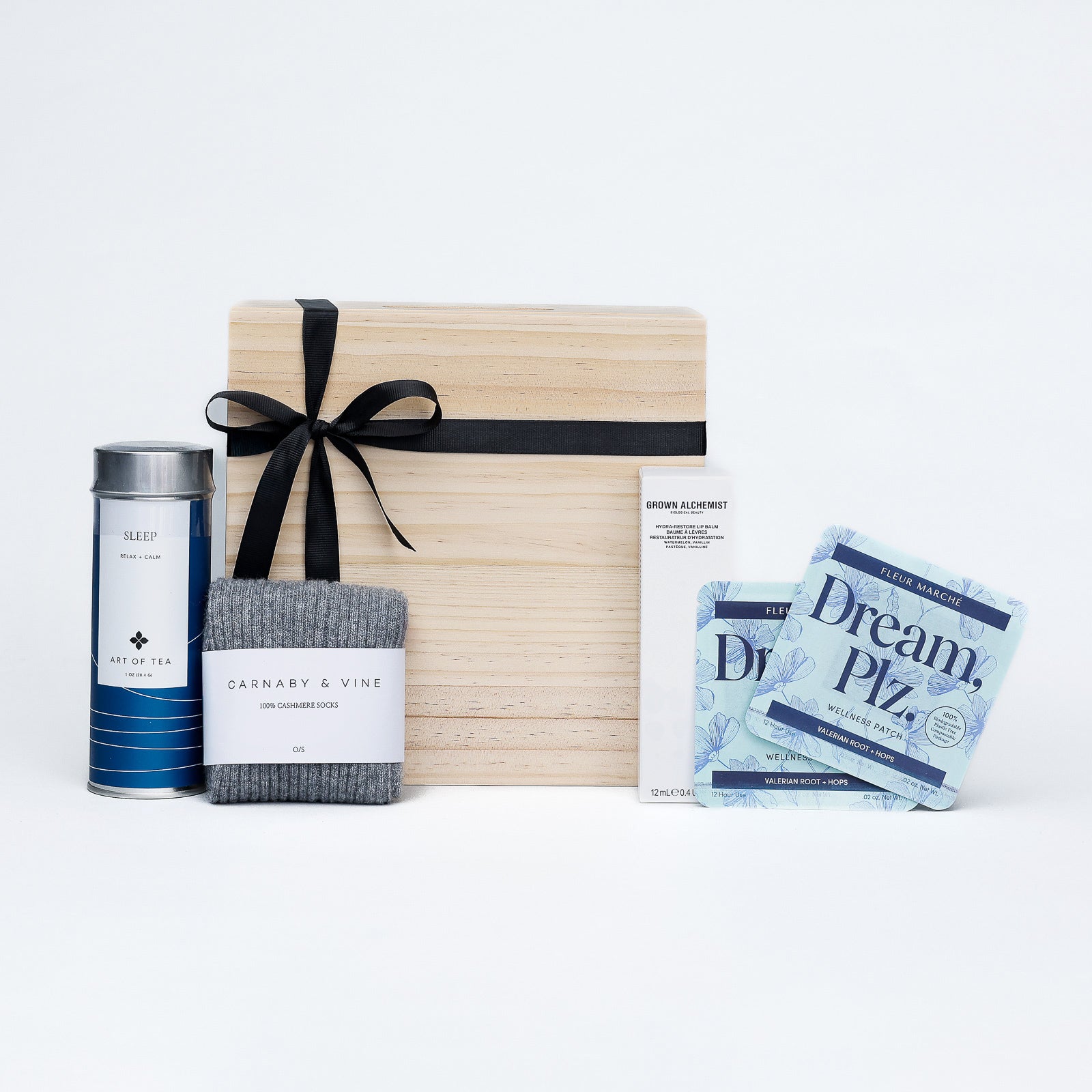Gift set with a wooden box, tea canister, socks, and packets on a white background