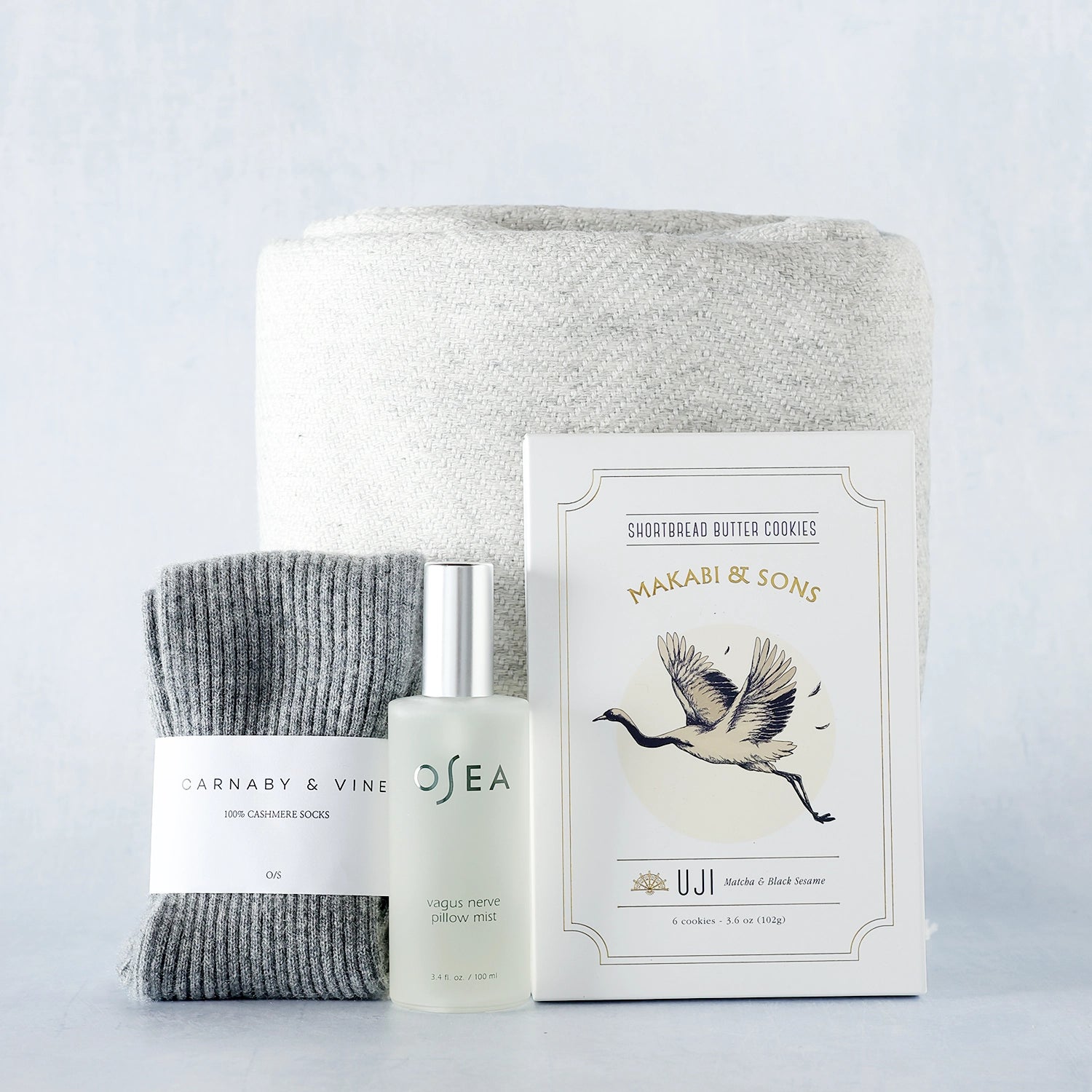 Product display with a sleep spray, blanket, cookies and socks on a light gray background