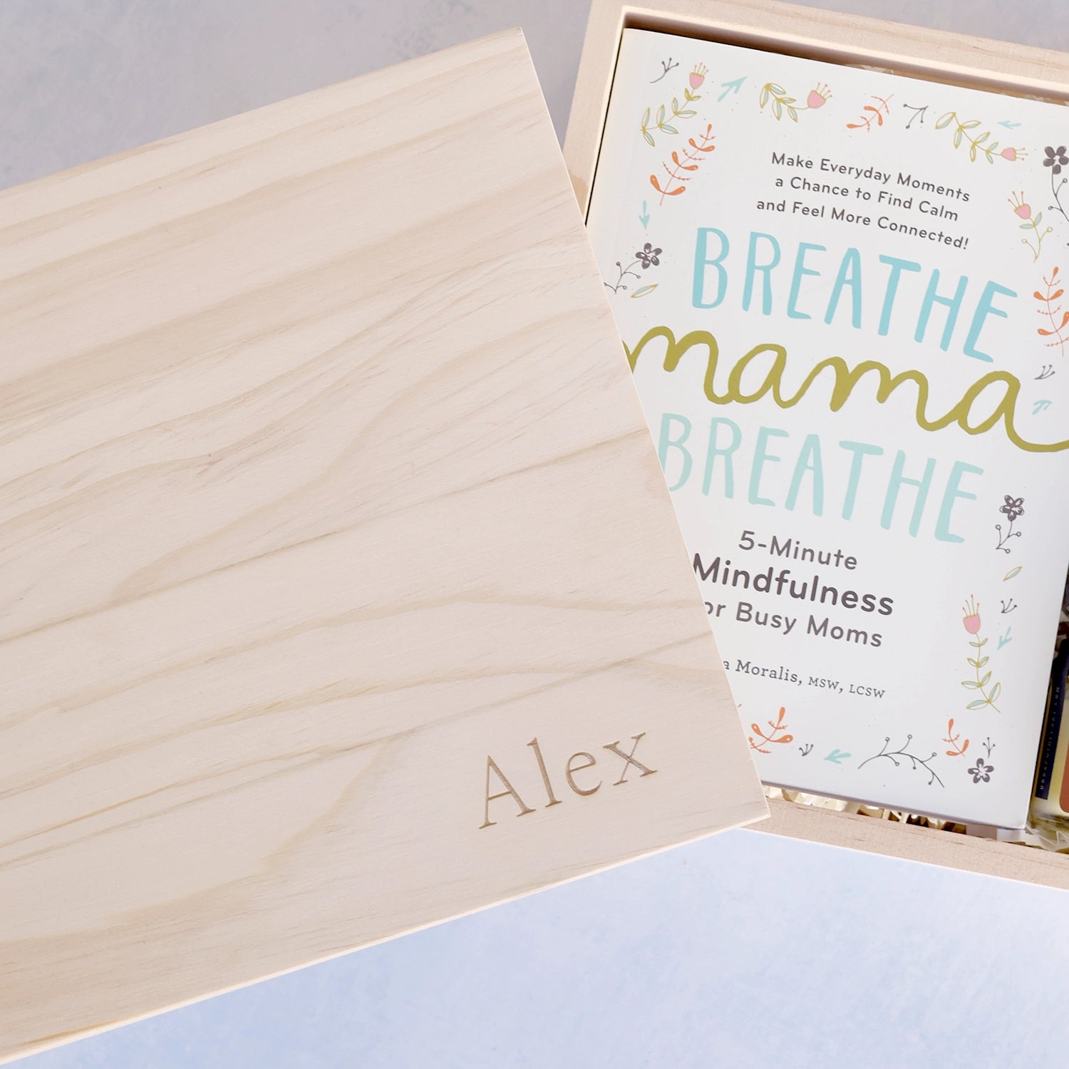 Close up of a parenting book titled 'Breathe Mama Breathe' in a wooden box with a name engraved on the lid.
