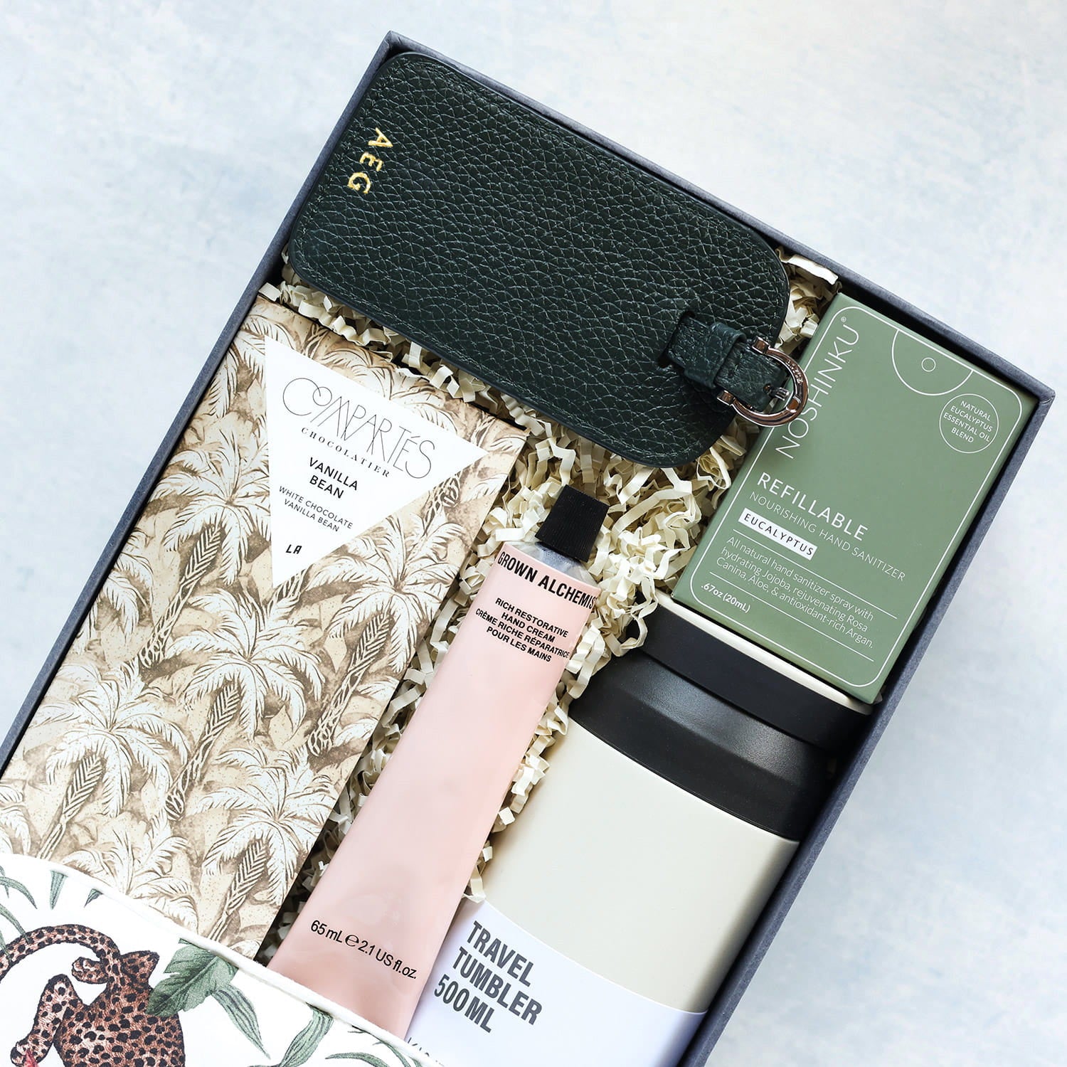 Gift set with monogrammed luggage tag, travel mug, hand lotion, and other items in a box