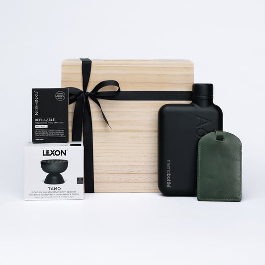 Gift set with wooden box, black water bottle, and green luggage tag on a light gray background